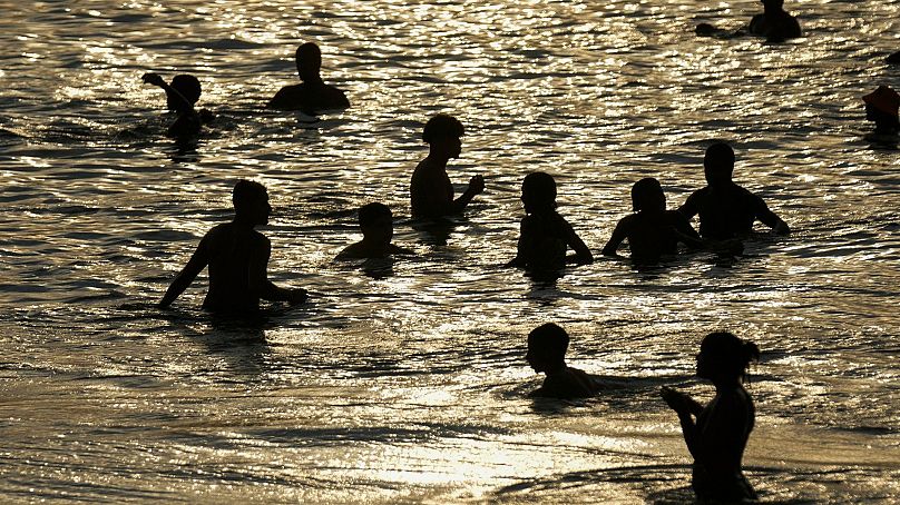 People cool off in the shallow waters of Arpoador beach amid a heat wave, in Rio de Janeiro, Brazil.