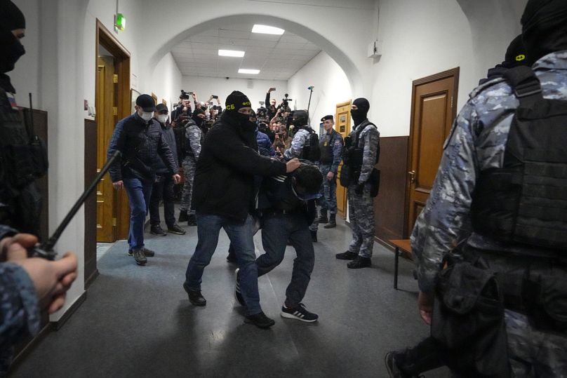 A suspect in the Crocus City Hall shooting on Friday is escorted by police officers in the Basmanny District Court, in Moscow, Russia