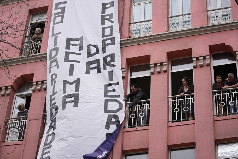 Ein großes Transparent mit der Aufschrift "Solidarität vor Eigentum" wird während einer Demonstration in Lissabon am Samstag, den 1. April 2023, an einem Wohnhaus entrollt.