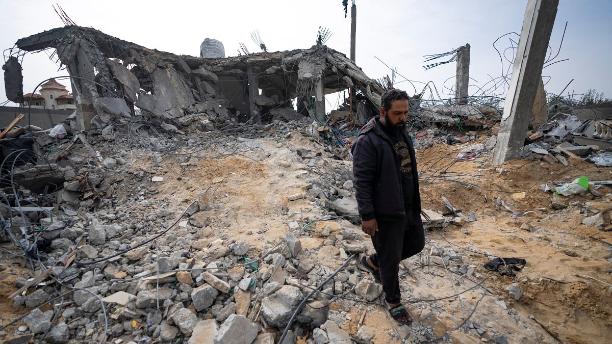 فلسطينيون ينظرون إلى منزل دمرته غارة إسرائيلية في رفح، قطاع غزة يوم الثلاثاء، 26 مارس/آذار 2024