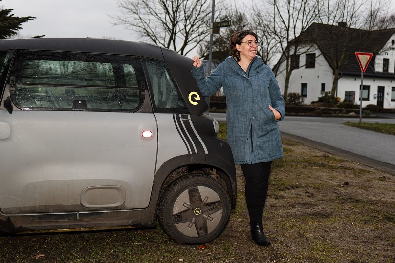 Astrid Nissen, resident of the village of Sprakebuell, stands next to an electric car in Sprakebuell, Germany.