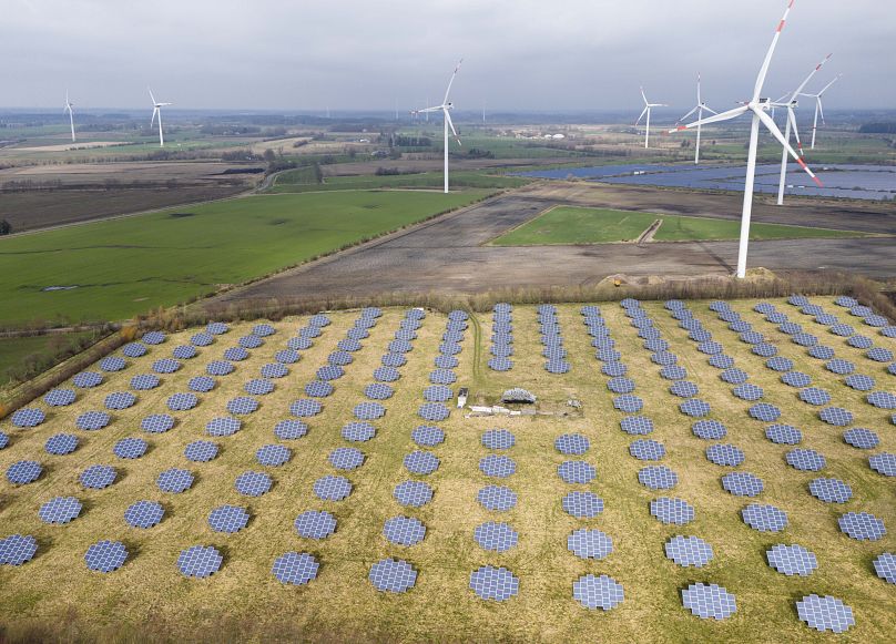 Solar panels stand on the edge of a wind farm in Sprakebuell, Germany.