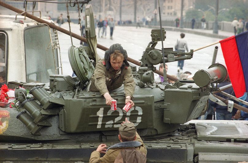 A soldier gives two cans of Coca-Cola to his friend-tank driver near the Russian Federation building in Moscow, August 1991
