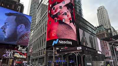 Pedestrians walk past the Nasdaq building in New York on Tuesday, March 26, 2024. 
