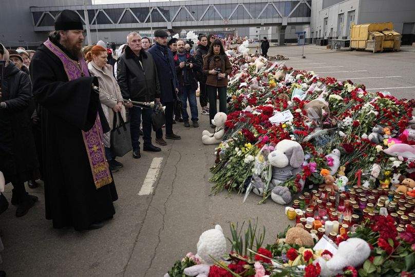 An Orthodox priest conducts a service at a makeshift memorial in front of the Crocus City Hall on the western outskirts of Moscow, Russia, Tuesday, March 26, 2024.