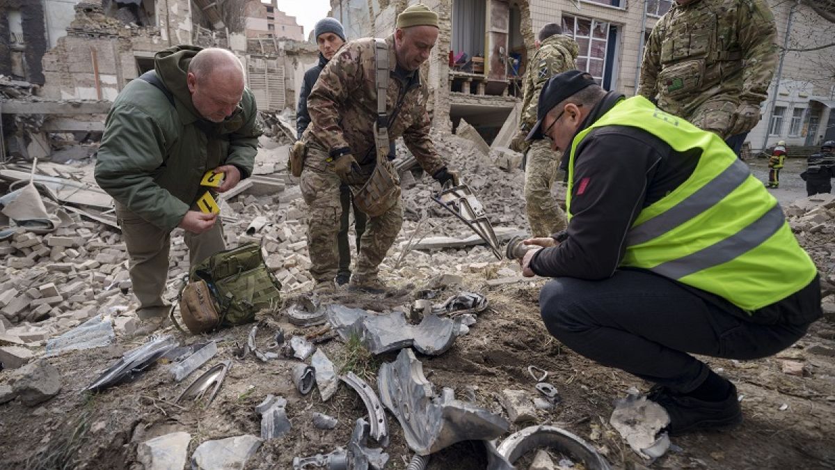 Ukrán katonai szakértők egy rakéta maradványait gyűjtik egy lerombolt épület mellett a Pecserszkij kerületben, egy orosz légitámadás után az ukrajnai Kijevben 2024. március 25