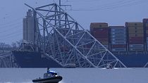 A container ship rests against wreckage of the Francis Scott Key Bridge as night falls on Tuesday, March 26, 2024, as seen from Sparrows Point, Md.