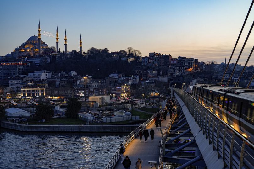 Backdropped with Suleymaniye mosque, pedestrians walk along Halic bridge metro station, March 2024