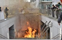 A protestor walks by a fire burning in a stairwell near the metro station during a demonstration outside the European Council building in Brussels, Tuesday 26 March.