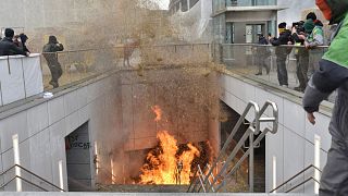 A protestor walks by a fire burning in a stairwell near the metro station during a demonstration outside the European Council building in Brussels, Tuesday 26 March.