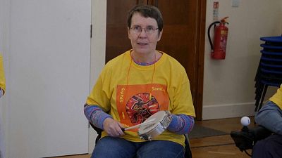 A woman in a samba drum class for people with Parkinson's disease.