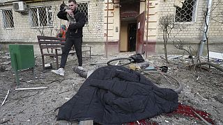 Un hombre evacúa a su perro mientras pasa junto al cadáver de un hombre muerto por un ataque ruso en Járkov, Ucrania, el miércoles 27 de marzo de 2024.