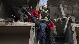 Ciudadanos palestinos transportan el cadáver de una mujer hallado bajo los escombros de un edificio destruido tras un ataque aéreo israelí en Rafah, Franja de Gaza.
