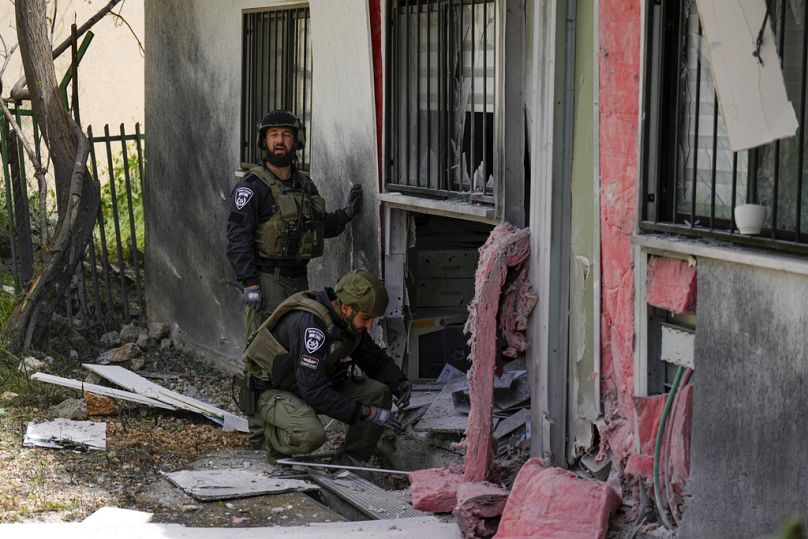 Israeli security forces examine the site hit by a rocket fired from Lebanon, in Kiryat Shmona, March 2024
