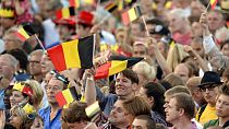 People wave Belgian flags as royal family members arrive outside of the national ball in the Marolles district of Brussels on Saturday, July 20, 2013.