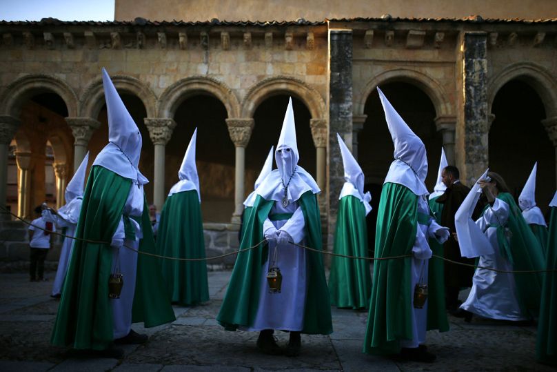 Penitentes encapuchados de la hermandad 'La Oracion en el Huerto' se reúnen en la iglesia de San Lorenzo antes de unirse a una procesión de Semana Santa en Segovia, España.