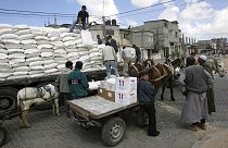 Varios ciudadanos descargan un camión que transporta ayuda humanitaria y alimentos.