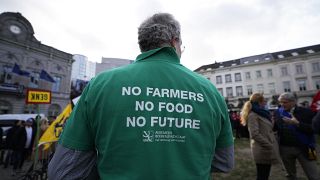 A farmer wears a shirt with a message during a demonstration of French and Belgian farmers outside the European Parliament in Brussels, on 24 January.