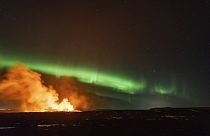 Volcán en erupción con la auroraboreal de fondo cerca de Grindavik