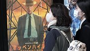 İnsanlar Tokyo'da "Oppenheimer" filmini tanıtan bir posterin yanından geçiyor, 29 Mart 2024 