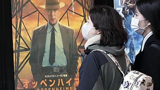İnsanlar Tokyo'da "Oppenheimer" filmini tanıtan bir posterin yanından geçiyor, 29 Mart 2024 