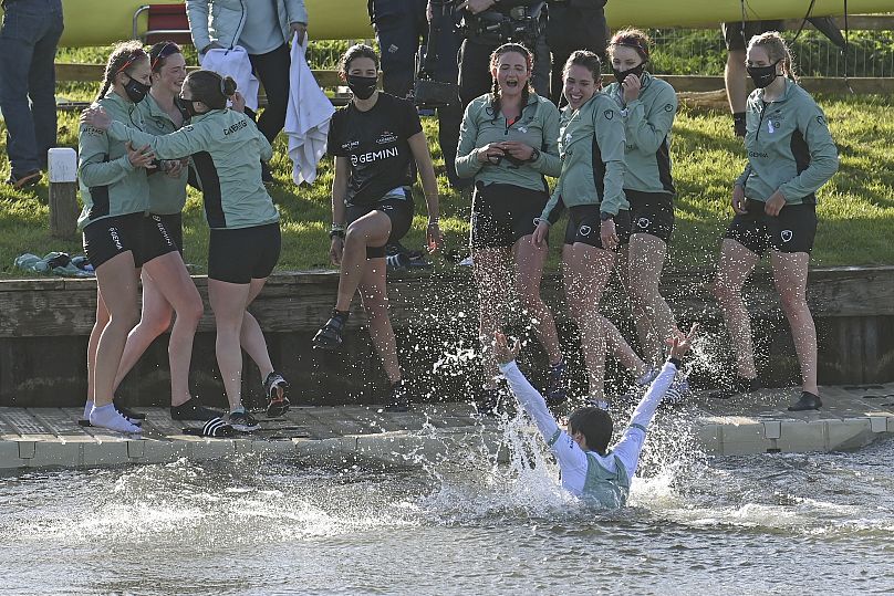 Cambridge cox Dylan Whitaker reacts after he was thrown into the water by his crew as they celebrate after beating Oxford to win the Varsity Women's Boat Race in 2021