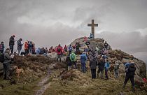 Grupo de personas rezando después de caminar hasta la Cruz de Rylstone en Barden Moor para conmemorar el Viernes Santo, cerca de Ripponden, Inglaterra, el 29 de marzo de 2024.