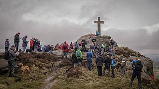 Grupo de personas rezando después de caminar hasta la Cruz de Rylstone en Barden Moor para conmemorar el Viernes Santo, cerca de Ripponden, Inglaterra, el 29 de marzo de 2024.