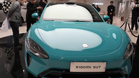 Visitors to the Xiaomi Automobile flagship store look at the Xiaomi SU7 electric car on display in Beijing, Tuesday, March 26, 2024.