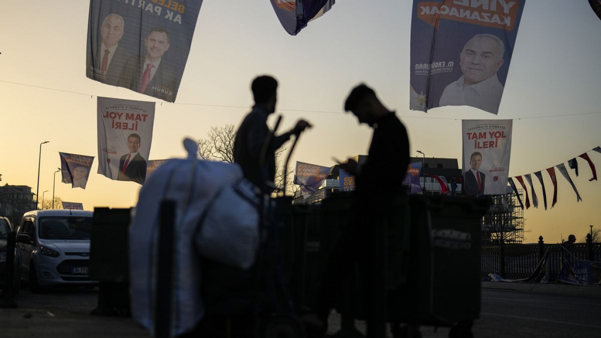 People walk under campaign banners of candidates for Istanbul of Justice and Development Party, or AKP, and Republican People's Party, or CHP, in Istanbul