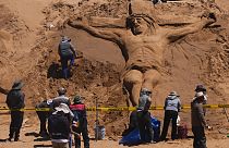 Einer Sandskulptur, die Jesus Christus am Kreuz darstellt, in Los Arenales de Cochiraya, am Stadtrand von Oruro. 30. März 2024