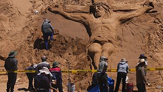 Einer Sandskulptur, die Jesus Christus am Kreuz darstellt, in Los Arenales de Cochiraya, am Stadtrand von Oruro. 30. März 2024