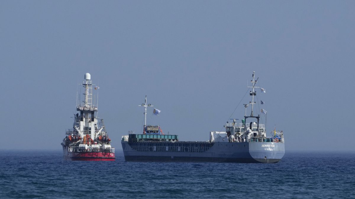 A cargo ship, right, and a ship belonging to the Open Arms aid group prepare to set sail outside the port of Larnaca, Cyprus, on Saturday, March 30, 2024. Cypriot port of