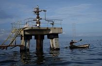 یک ماهیگیر در تاریخ ۱۲ اکتبر ۲۰۲۲ از کنار یک مته غیرفعال حفاری نفت در دریاچه ماراکایبو در ونزوئلا عبور می کند.