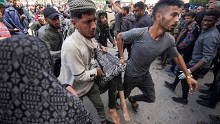 فلسطينيون يحملون جريحاً بعد غارة جوية إسرائيلية استهدفت خيماً بالقرب من مستشفى الأقصى في دير البلح