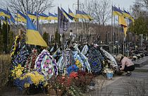 Nő ápolja harcban elesett rokonának sírját a Kijev külvárosában lévő bucsai temetőben 2024. március 30-án, szombaton. 