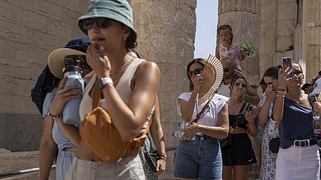 Turisti posjećuju drevno brdo Akropole tijekom toplinskog vala u Ateni, Grčka, u srpnju 2023