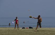 A man and woman play racketball on the beach during a hot day in southern coastal city of Larnaca on the Mediterranean island of Cyprus, Sunday, 31 March 2024