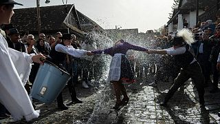 مجموعة من الرجال يسكبون دلاء من المياه على سيدات باحتفال تقليدي يمارسه سكان قرية هولوكو 