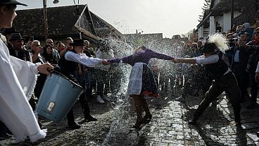 مجموعة من الرجال يسكبون دلاء من المياه على سيدات باحتفال تقليدي يمارسه سكان قرية هولوكو 
