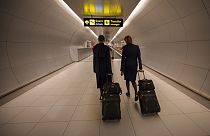 Flight attendants arriving at the Henri Coanda International Airport pass under a Schengen Information sign, in Otopeni, near Bucharest, Romania, Sunday, March 31, 2024. 