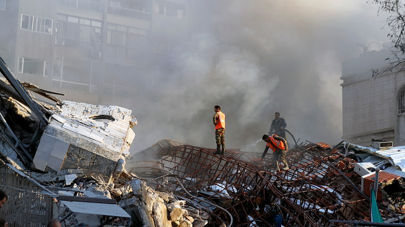Emergency services work at a destroyed building hit by an air strike in Damascus, Syria, Monday, April 1, 2024.