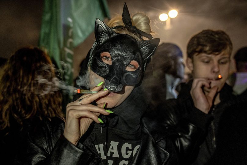 People smoke marijuana cigarette in front of the Brandenburg Gate during the 'Smoke-In' event in Berlin, Germany on Monday