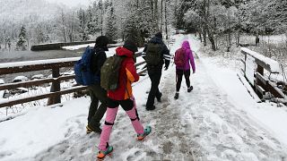 Imagen de varias personas caminando sobre un camino cubierto de nieve.