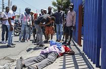 Des gens observent le corps d'un homme gisant dans la rue du quartier Delmas à Port-au-Prince, Haïti, le lundi 1er avril 2024.