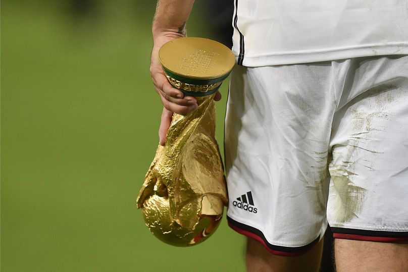 Germany's Lukas Podolski on the field in Rio de Janeiro, Brazil, on 13 July 2014, holding the World Cup trophy.
