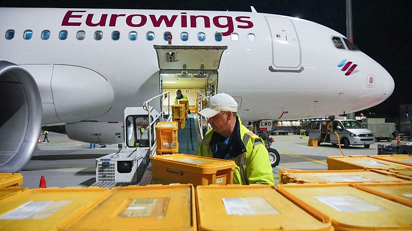 WISAG employees load a Eurowings Airbus bound for Stuttgart with plastic boxes full of mail, at Berlin Brandenburg Airport, in Schönefeld, Germany, 28 March 2024.