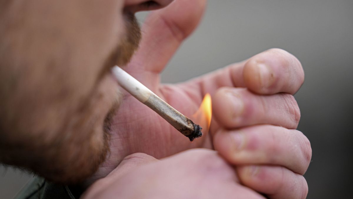 Мужчина курит каннабис перед Кафедральным собором в Кельне, Германия, во время публичного мероприятия, посвященного началу действия нового закона, в понедельник, 1 апреля.
