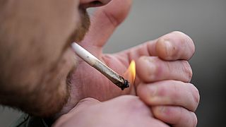 Un uomo fuma cannabis davanti alla Cattedrale di Colonia, in Germania, durante un evento di consumo pubblico all'inizio di una nuova legge, lunedì 1 aprile.
