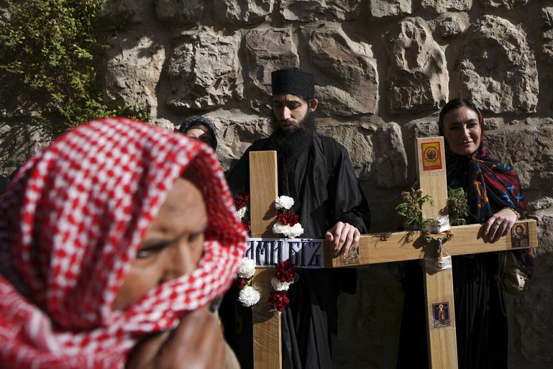 Muszlim férfi pénteki imára megy a ramadán alatt, míg ortodox keresztények a Via Dolorosán várják, hogy elkezdhessék a körmenetüket 2022 áprilisában